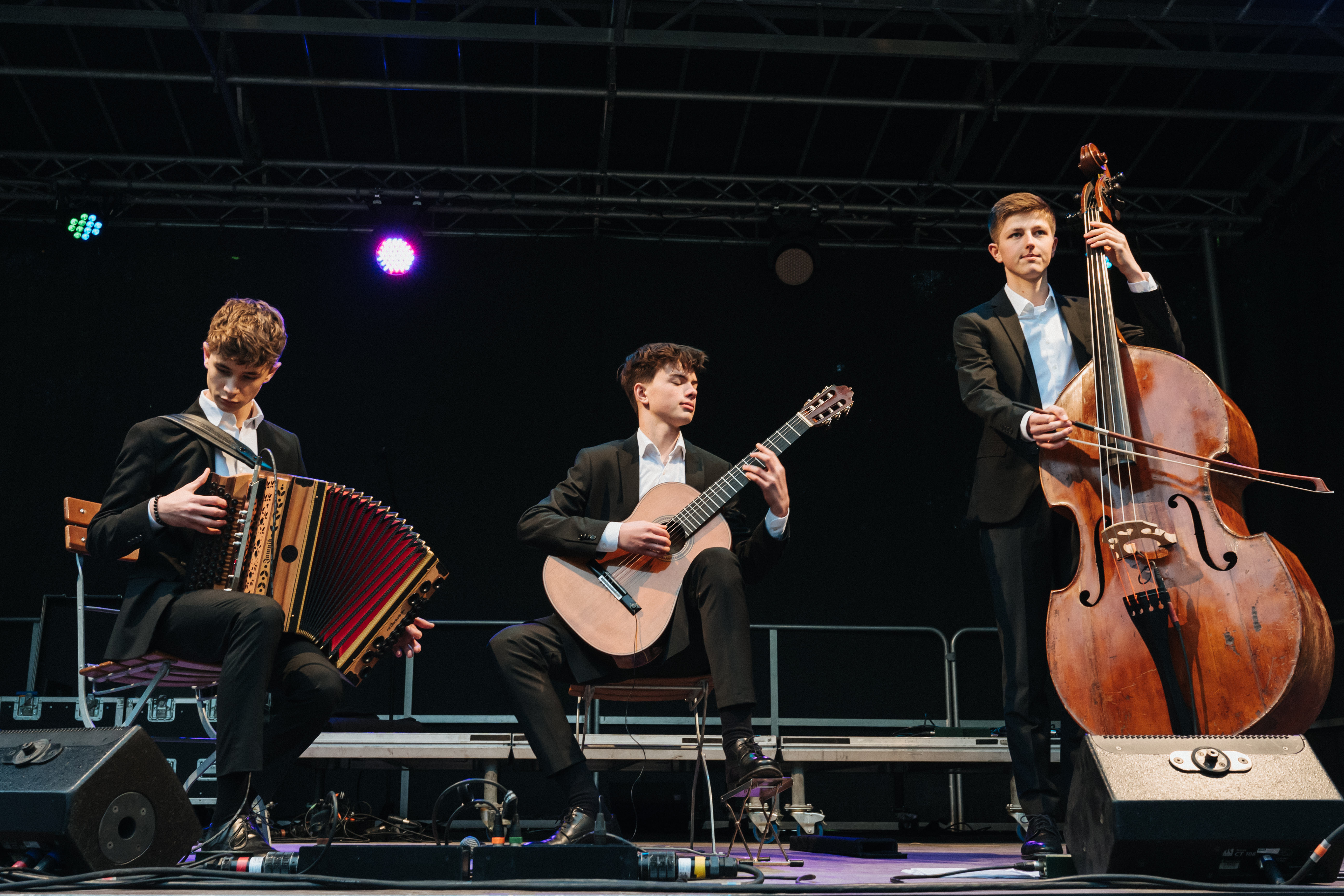 Konzert 34u-24 (c) Maria Montero Trio 34u, Jakob Kastner, Benno Panhans und Raphael Bauer auf der Bühne mit den Instrument Steirische Harmonika, Gitarre und Kontrabass